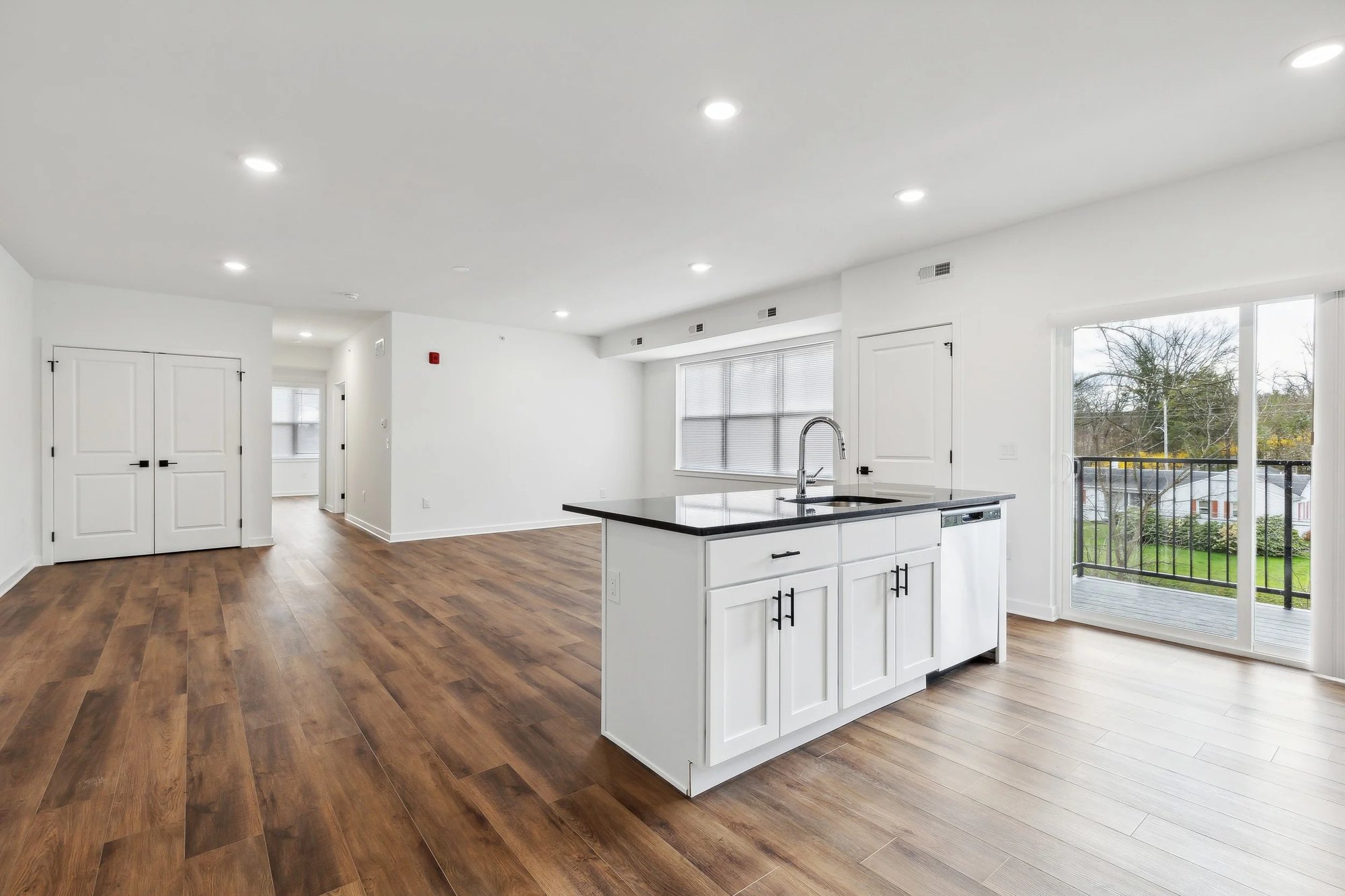 Open-concept living area and kitchen island with sliding door to balcony