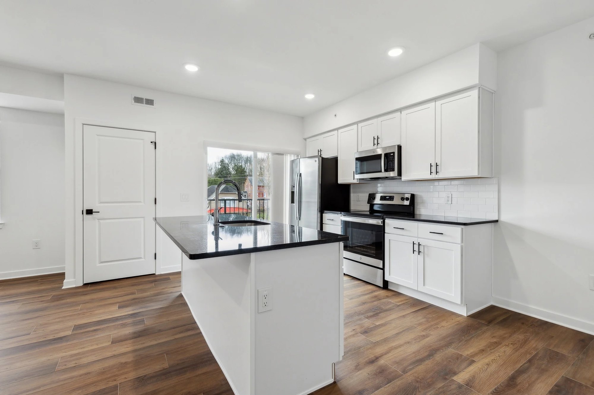 Apartment kitchen with stainless steel range, microwave, and island seating