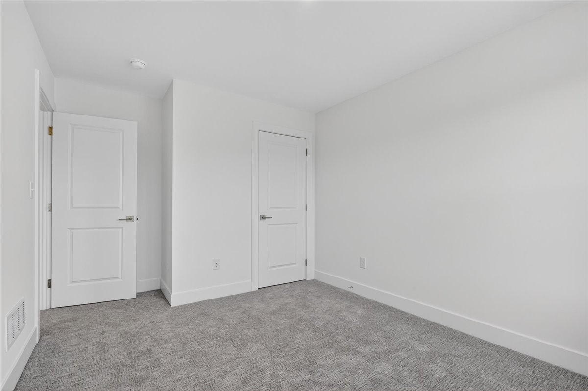 Secondary bedroom entry alcove with two paneled interior doors and neutral carpet