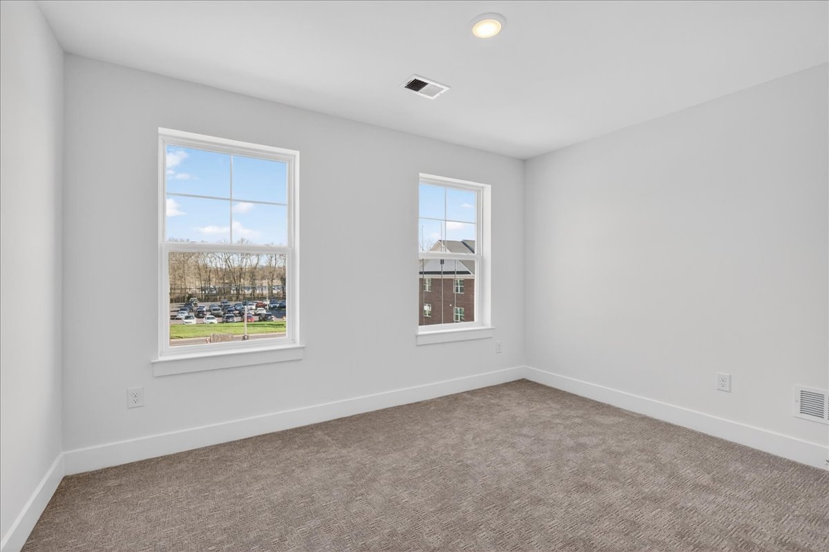 Secondary bedroom with plush carpet and two windows letting in natural light
