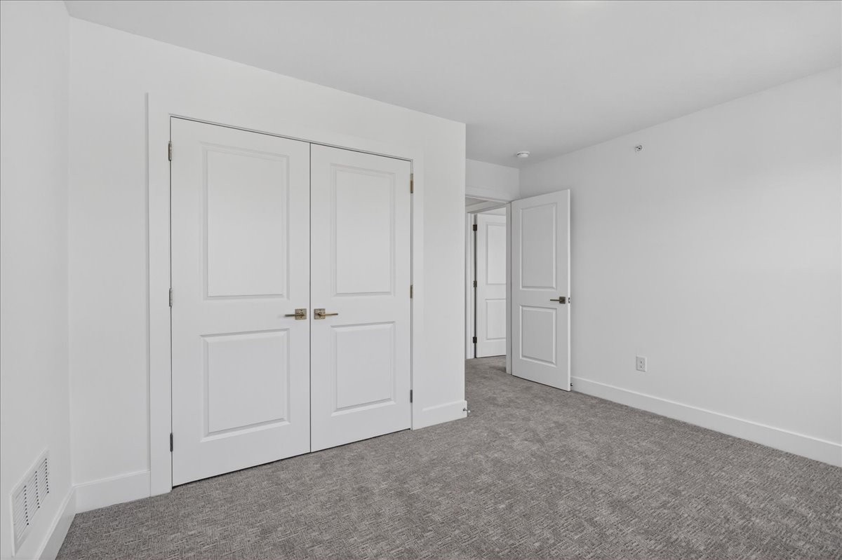 Secondary bedroom with a two-door white paneled closet and neutral carpet