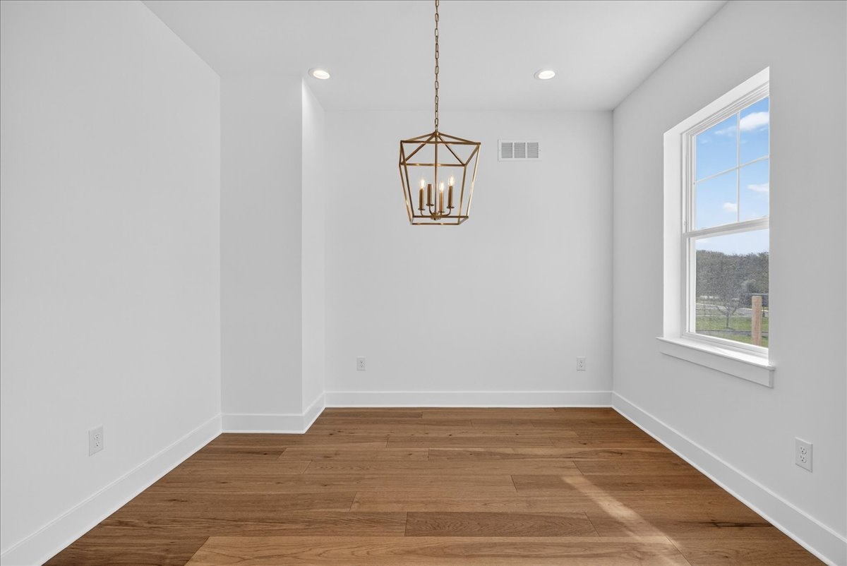 Dining room with a gold cage lantern chandelier and a large double-hung window with a rural view