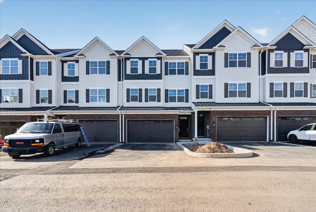 New Britain Place townhome exterior — brick fronts, white siding with dark gables, two-car garages on West Butler Avenue in New Britain Borough PA
