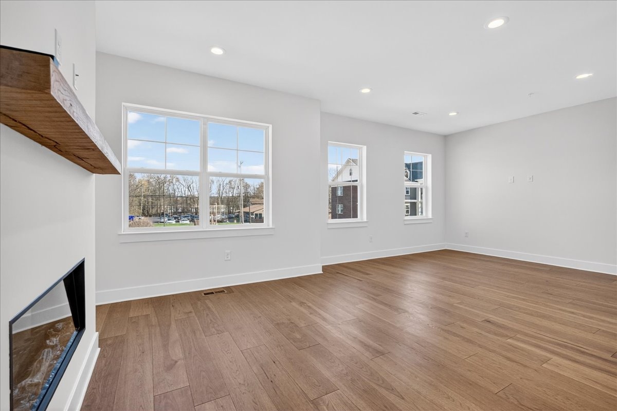 Great room with a wood-mantel fireplace, recessed lighting, and a wall of windows looking out to the neighborhood