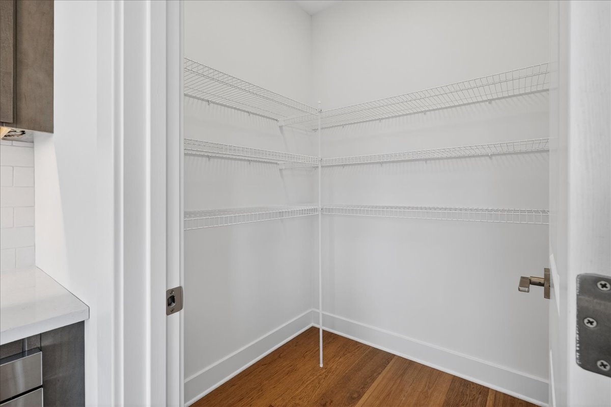 Walk-in pantry with wire shelving and hardwood flooring