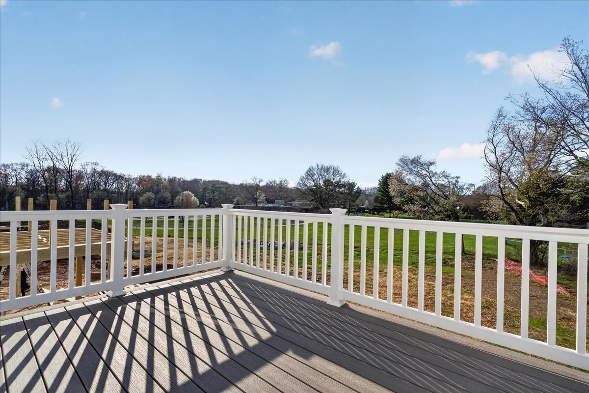 Rear composite deck with white vinyl railing overlooking open green space and mature trees at New Britain Place