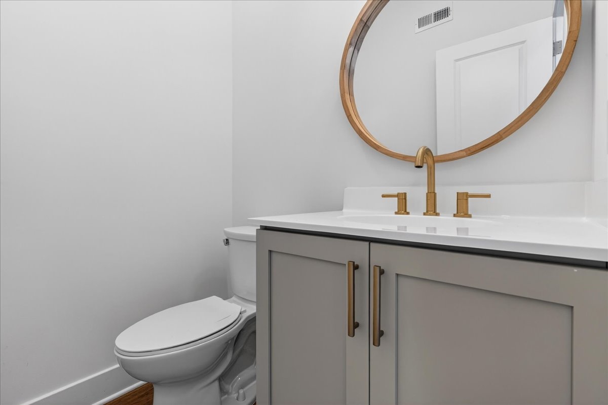 Secondary full bath with brass fixtures, gray shaker vanity, marble-look tile floor, and combination tub and shower