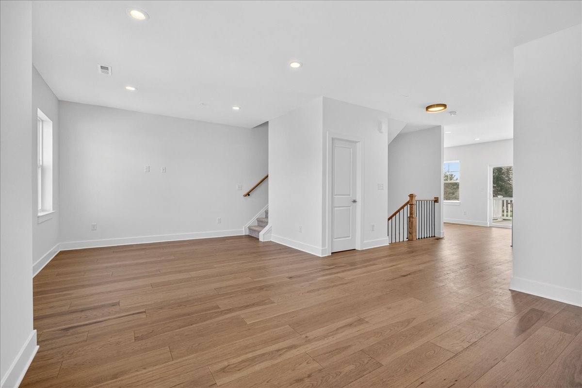 Upper-floor landing with hardwood, iron staircase railing, and open sightlines to secondary bedrooms